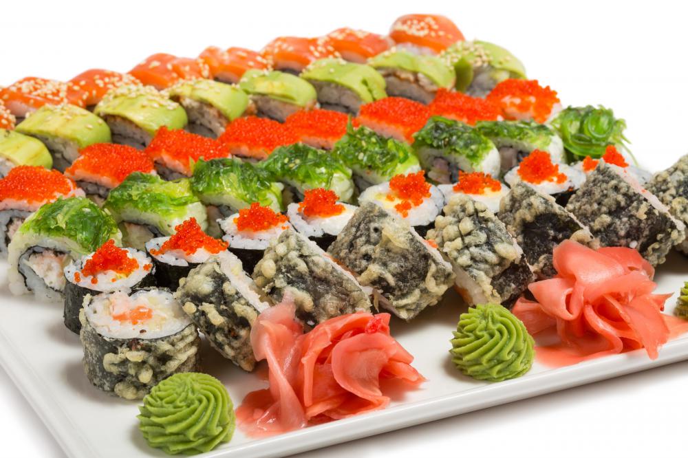 An array of various sushi types with wasabe and pickled ginger.