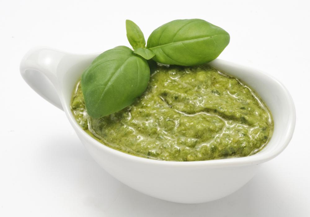 Bowl of pesto with basil leaves.