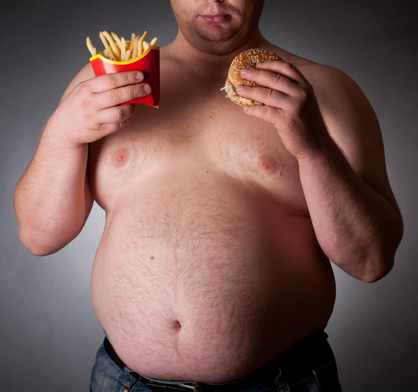 An overweight man with a fast food burger and fries.