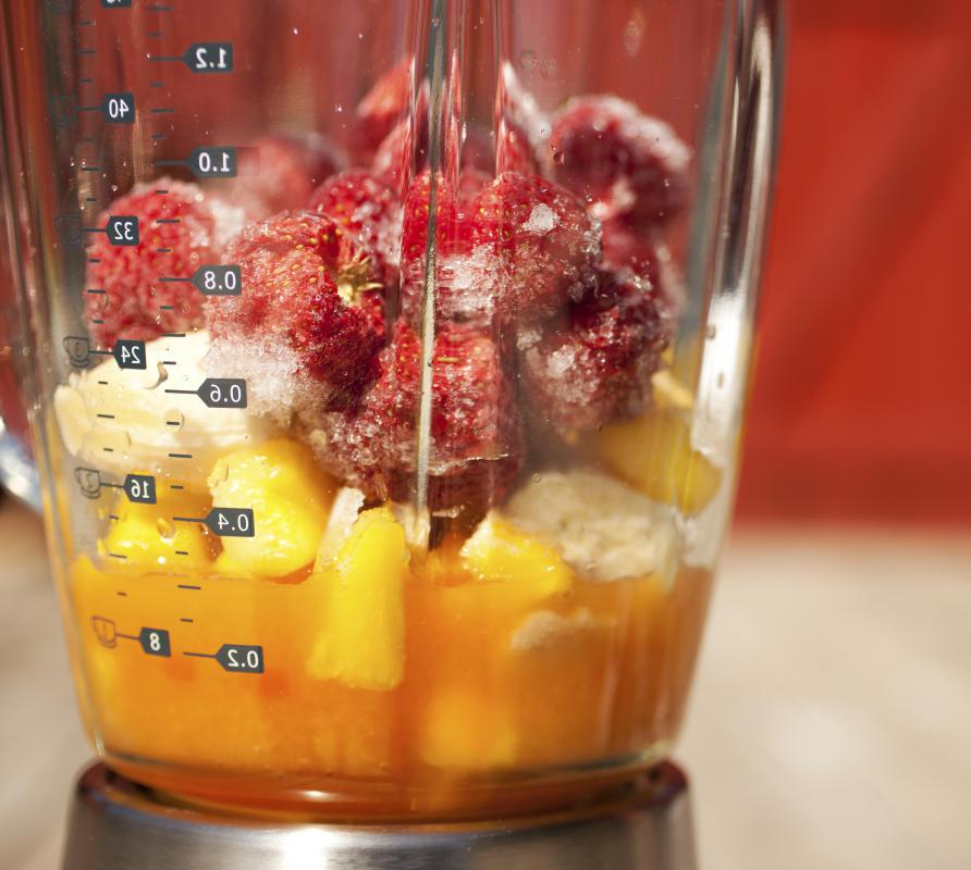 Various types of fruit, yogurt, and ice are blended together in a smoothie maker.