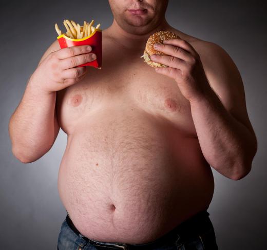 An overweight man with a fast food burger and fries.