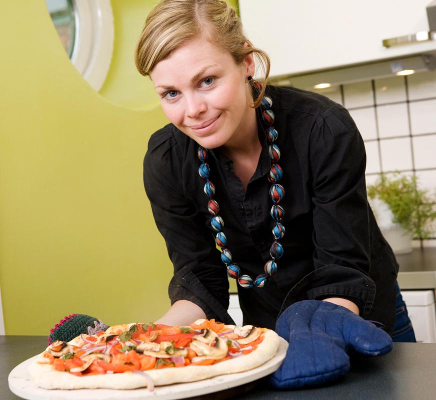 Chefs prepare pizza on a baking stone.