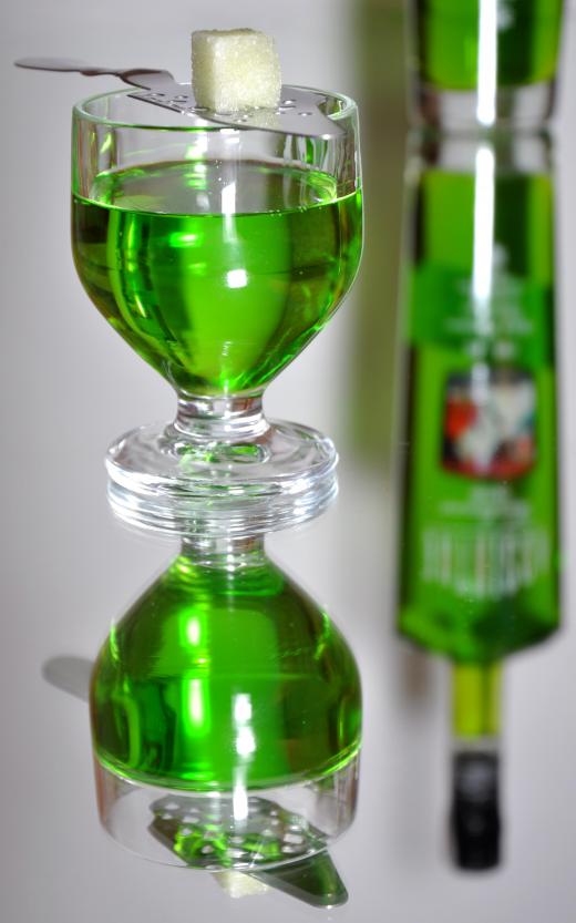 A small glass of absinthe with a sugar cube and absinthe spoon.