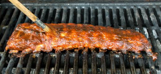 Baby back ribs are often marinated with barbecue sauce before being prepared on a grill.