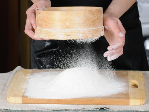 A woman using a drum sieve to sift flour.