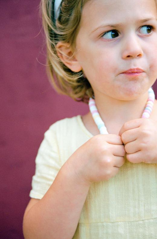 A little girl eating a candy necklace.