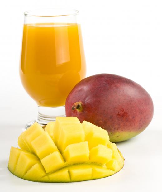 Mango nectar in a glass beside fresh mango.