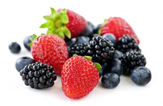 Blackberries beside strawberries and blueberries.