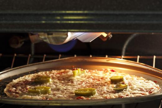 A pizza with jalapenos on it in an oven.