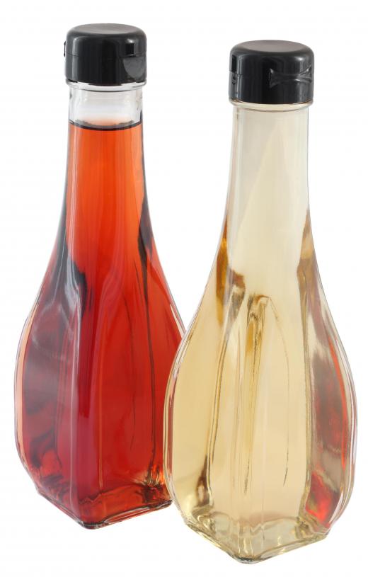 A bottle of white vinegar beside a bottle of red vinegar.