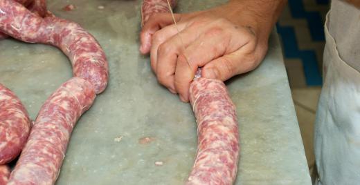 The pork filling for andouille sausage is seasoned with hot chili peppers before being packed into pork intestines casings.