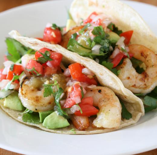 Shrimp tacos garnished with small pieces of fresh cilantro.