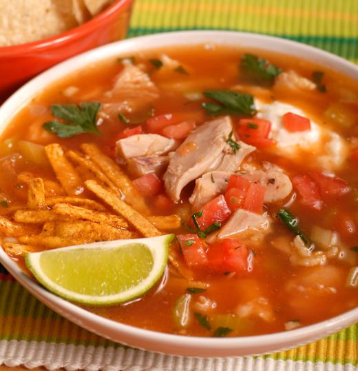 A bowl of tortilla soup with a wedge of lime.