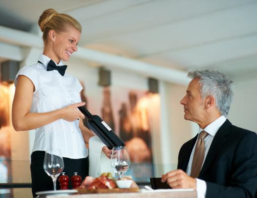 Waitress showing a bottle of wine to a oenophile.